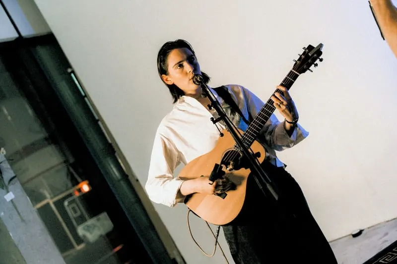 Musician performing with an acoustic guitar at an SJARK event