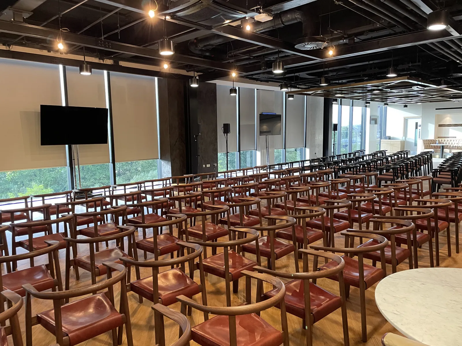 Conference room set for Caffè Nero with rows of leather chairs, screens and speakers