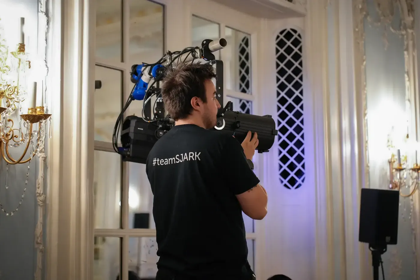 SJARK technician operating a camera and lighting in an ornate ballroom